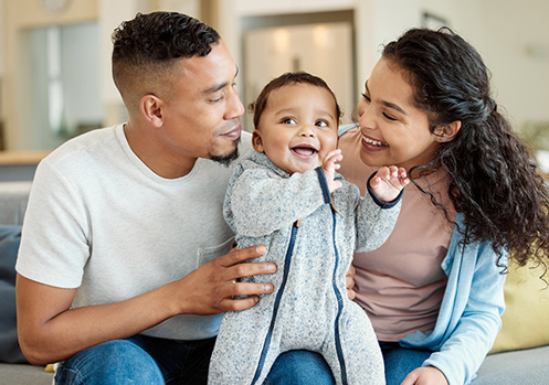 A young man and woman are holding up their baby